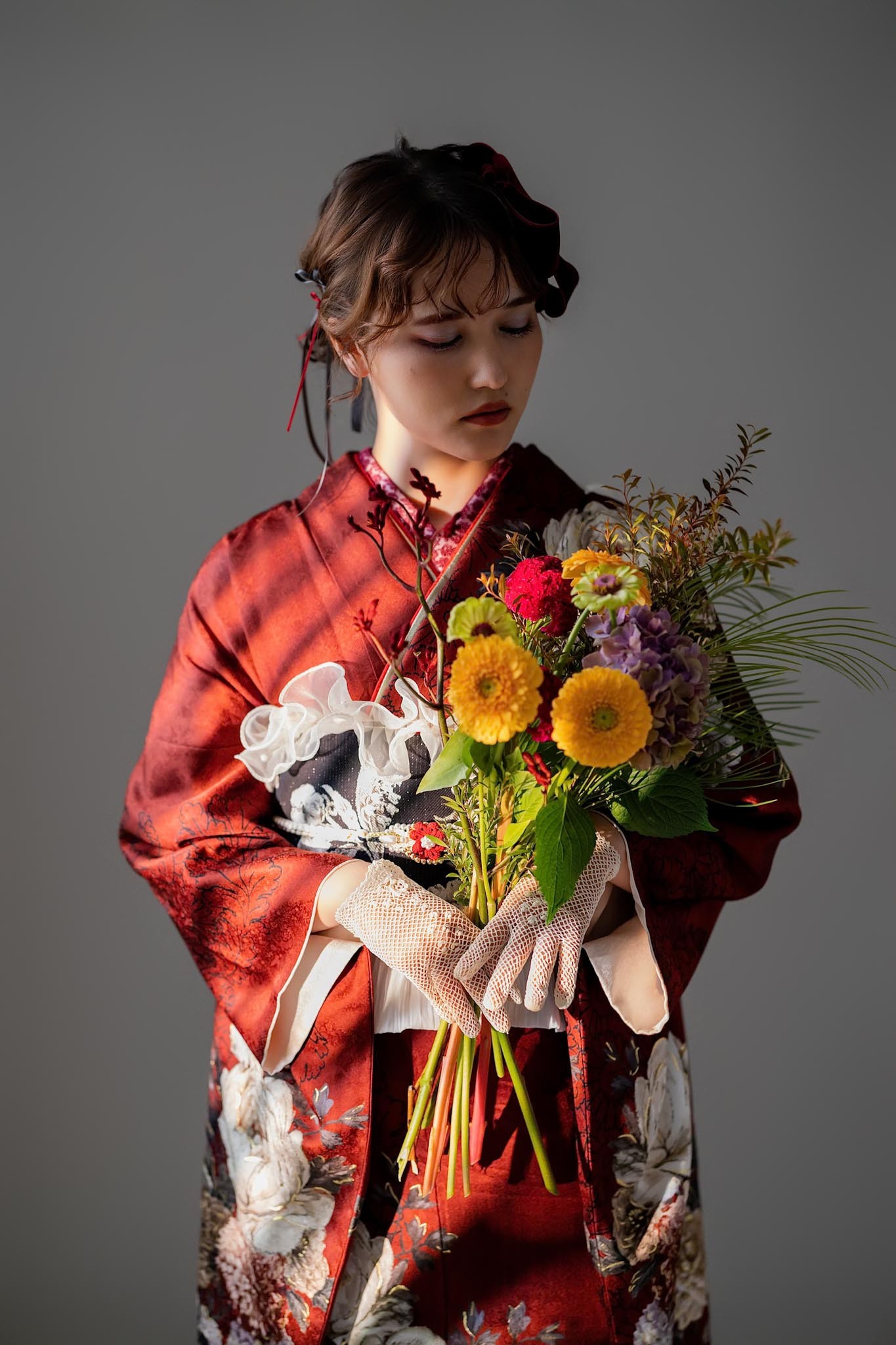 花束を持って赤い振袖で撮影した成人式のスタジオ写真