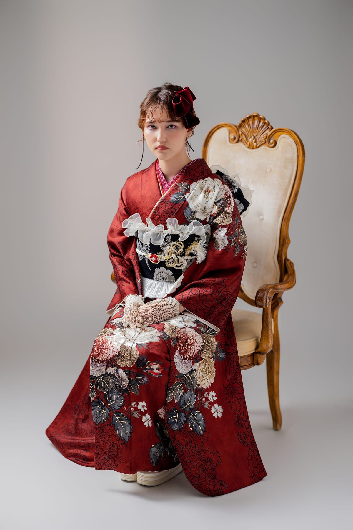 深紅に牡丹の振袖。金の椅子に座った姿