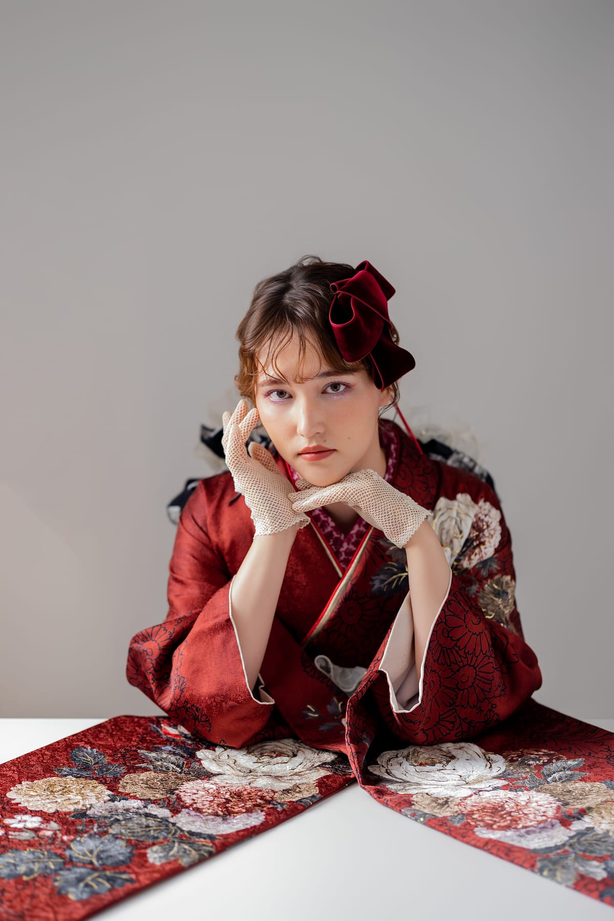 深紅に牡丹の振袖。椅子に腰かけて裾を広げた姿