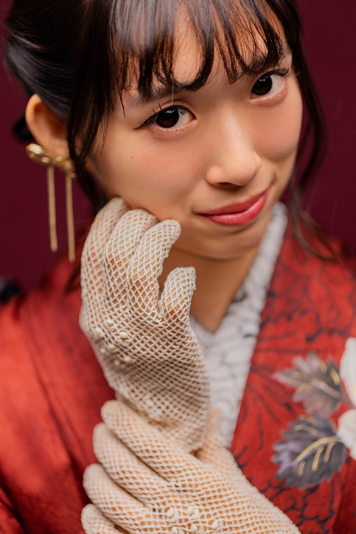 赤い振袖。レースの手袋をつけた手元を顔の横に添えた寄りです。成人式の前撮り写真