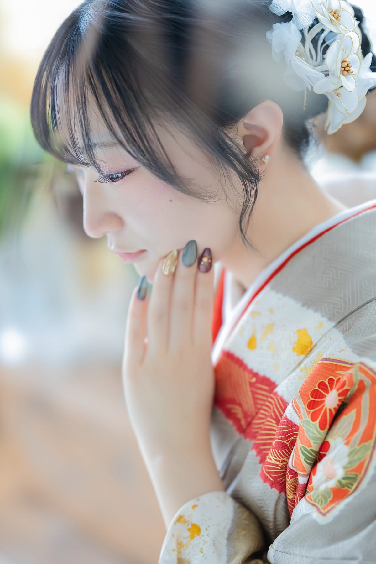 生成りに朱の花の振袖。手を顔の横に添えた寄りです。成人式の前撮り写真