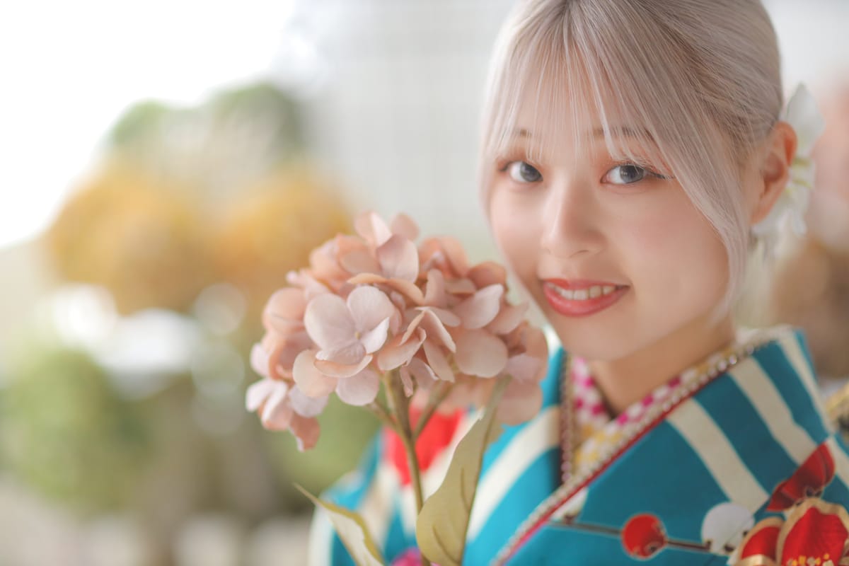 ターコイズの振袖で花を持って微笑む、成人式の前撮り写真