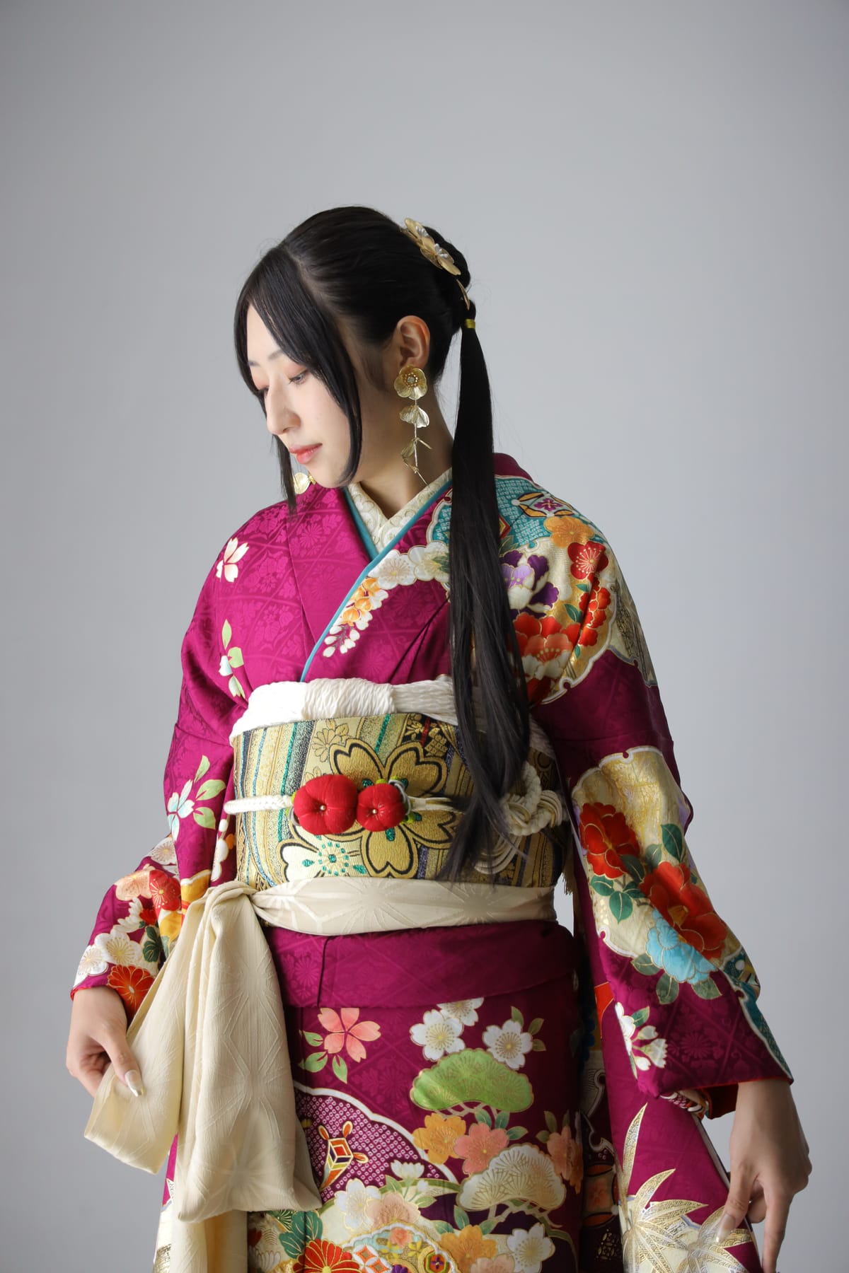 深紅にターコイズの振袖。振り返って帯を見せる姿です。成人式の前撮り写真
