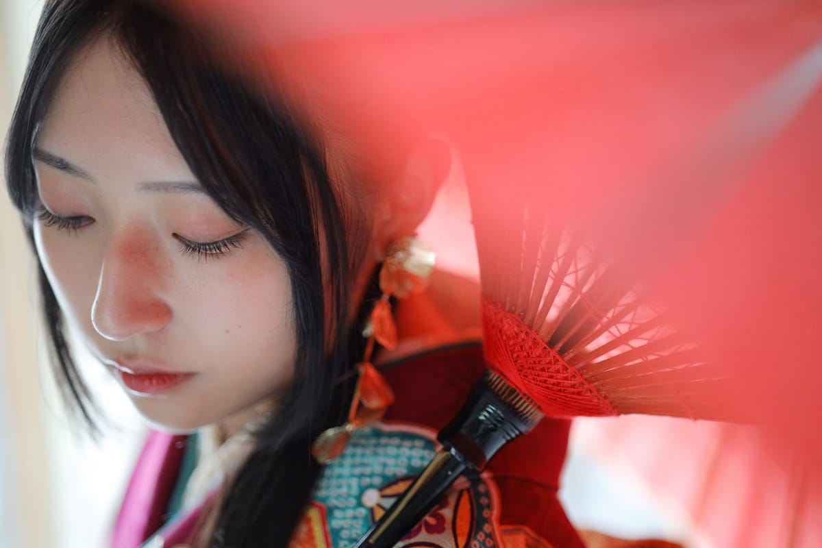 深紅にターコイズの振袖。カーテン越しの光の中に立つ姿です。成人式の前撮り写真