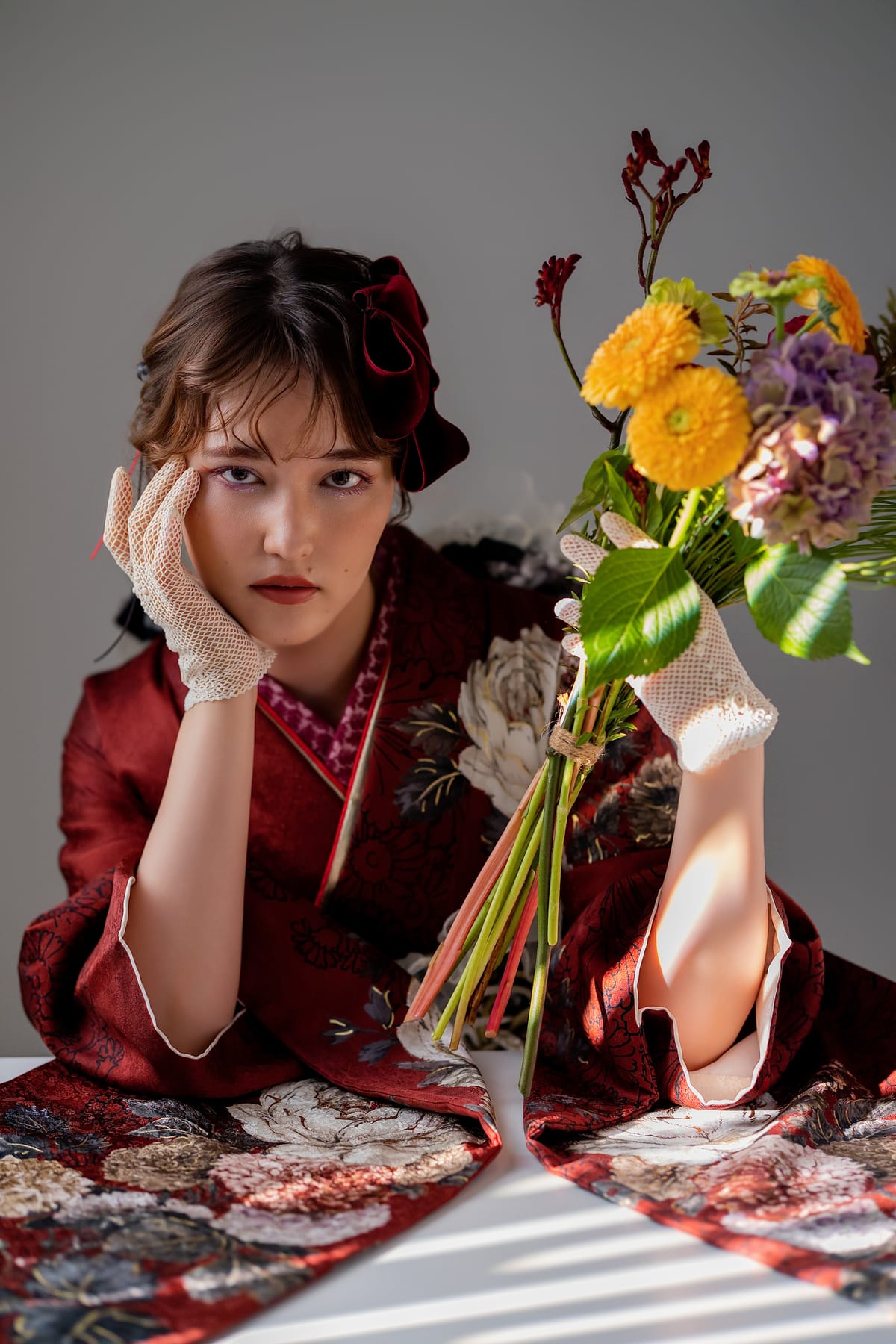 深いワインレッドの振袖。花束を持った上半身