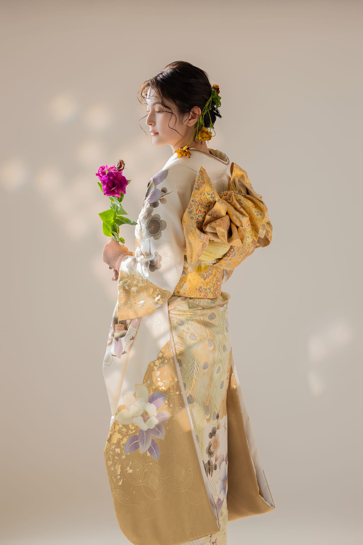白と金の淡い花柄の振袖。明るい背景での立ち姿