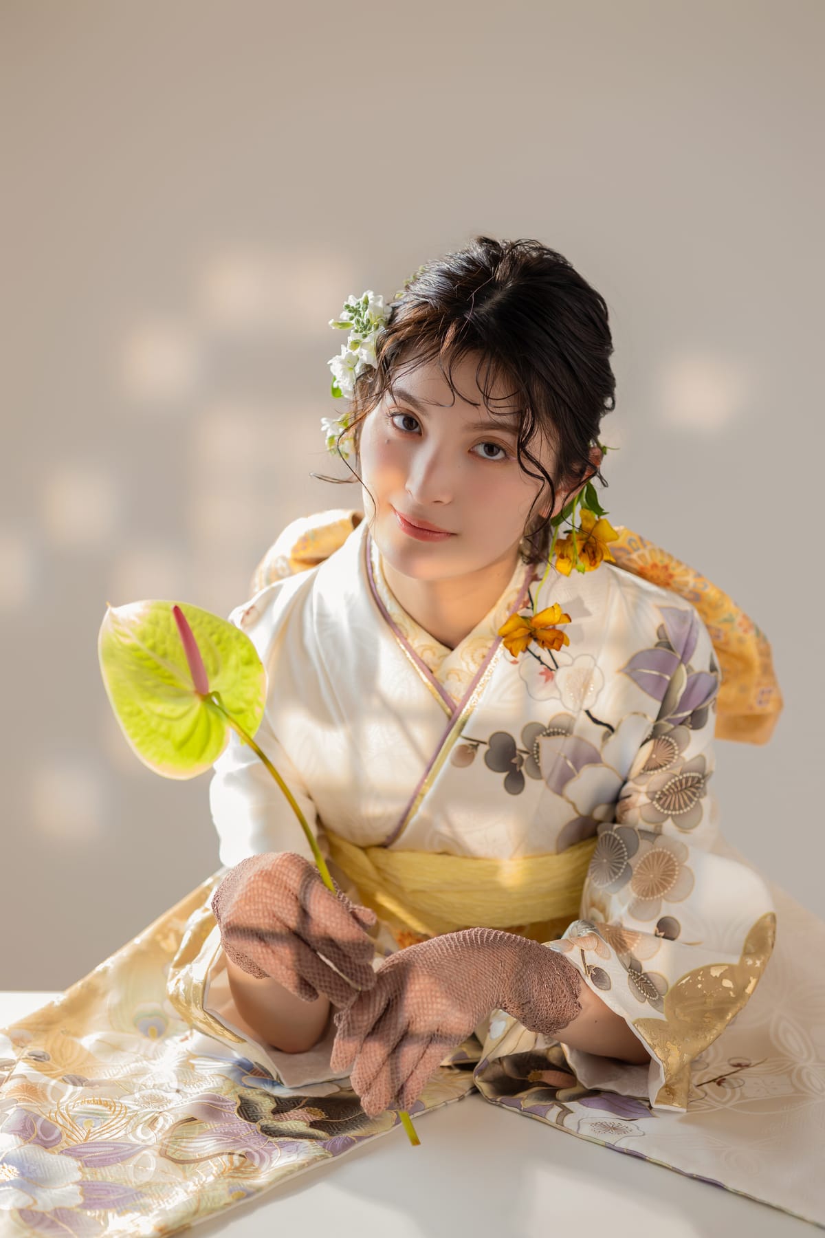 白と金の淡い花柄の振袖。花を手にした上半身