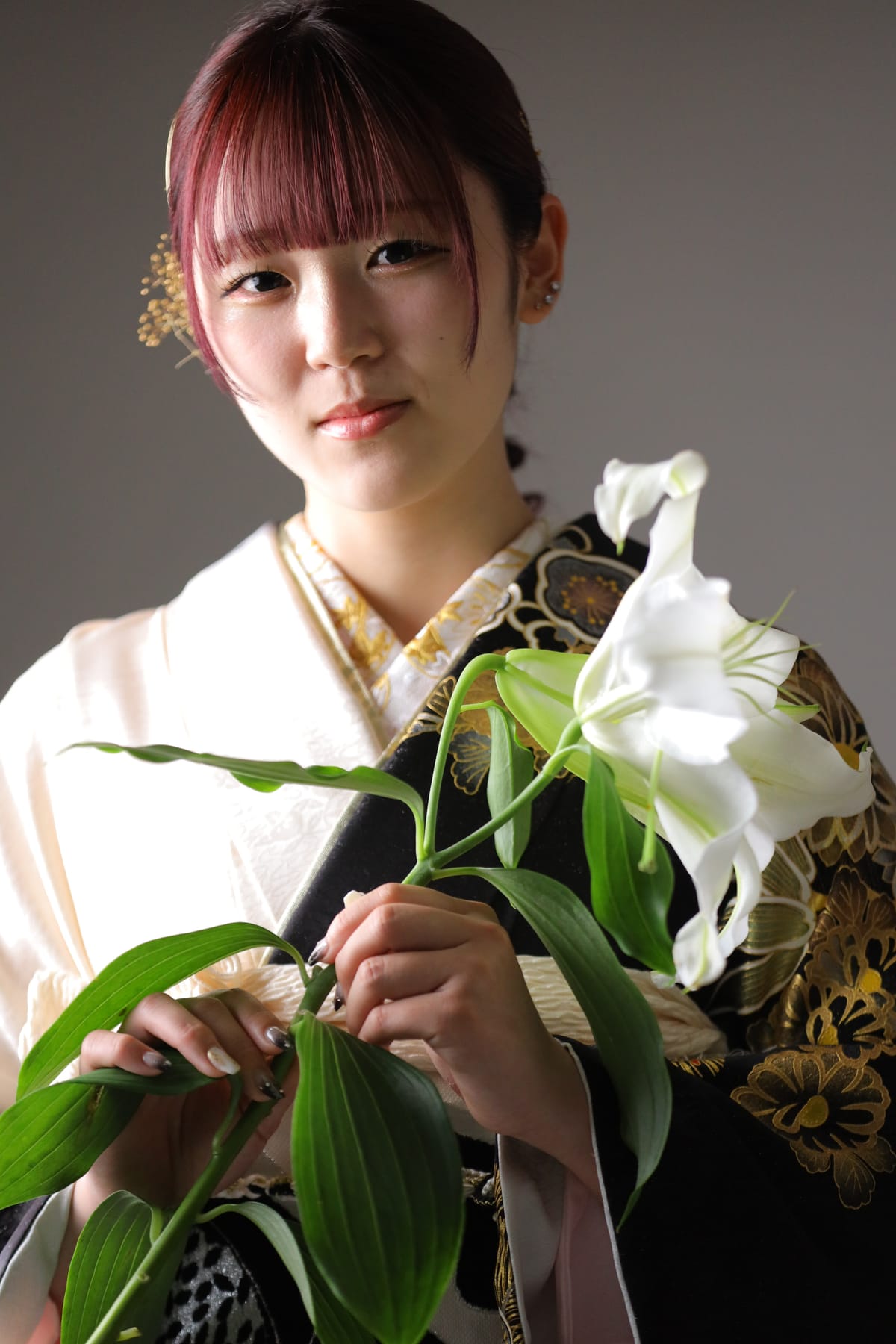 黒地に金の菊の振袖。白い百合を手にした上半身