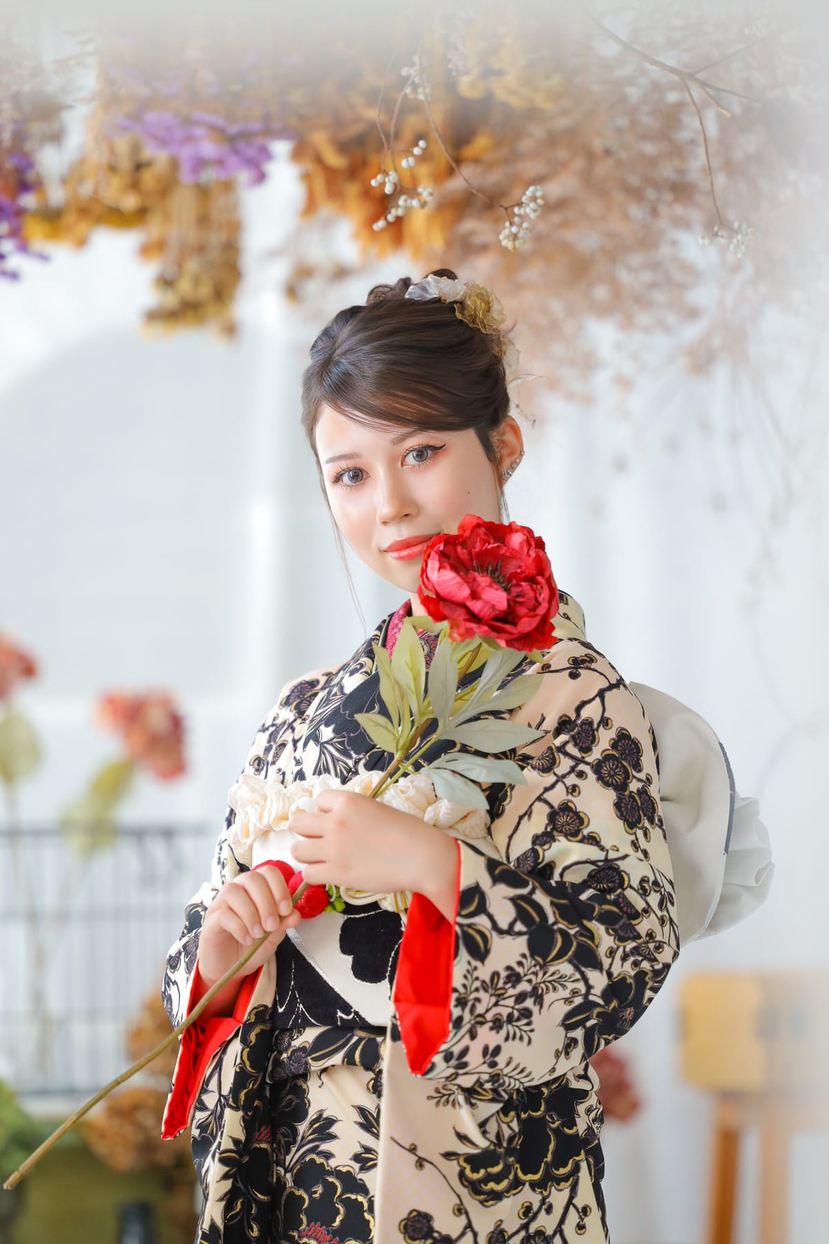 生成りに黒の花柄の振袖。赤い髪飾りと赤い小物を合わせた姿