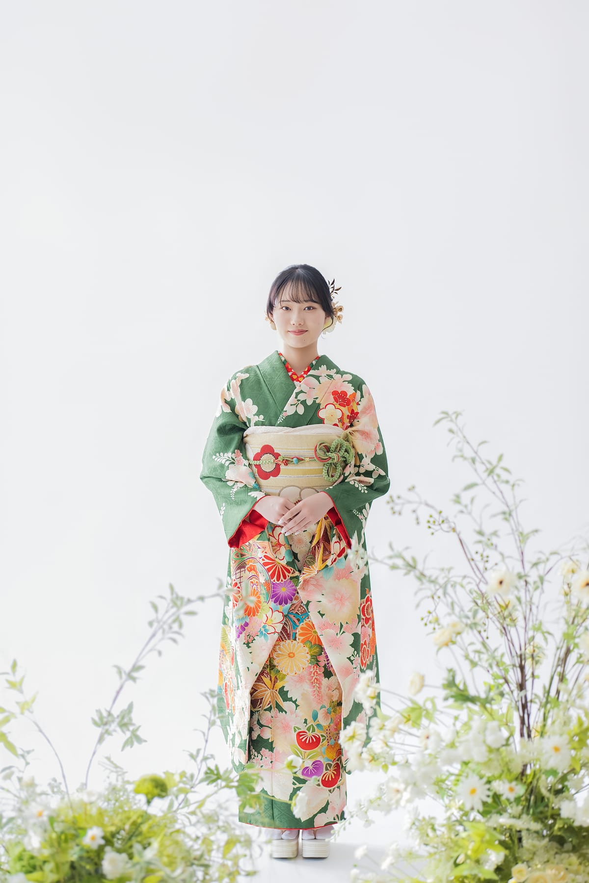 緑地に花の振袖。草花に囲まれて立つ全身