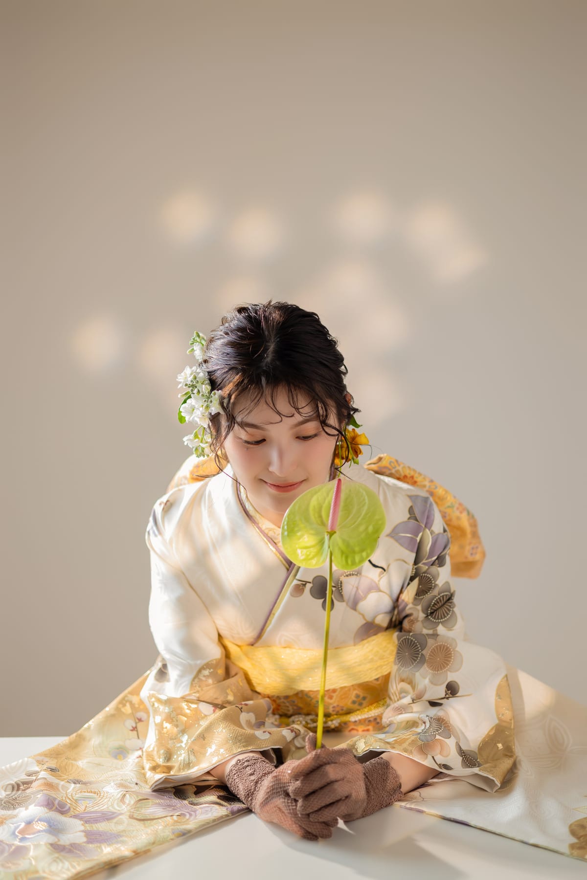 白地に花の振袖。目線を落として花を見つめる上半身