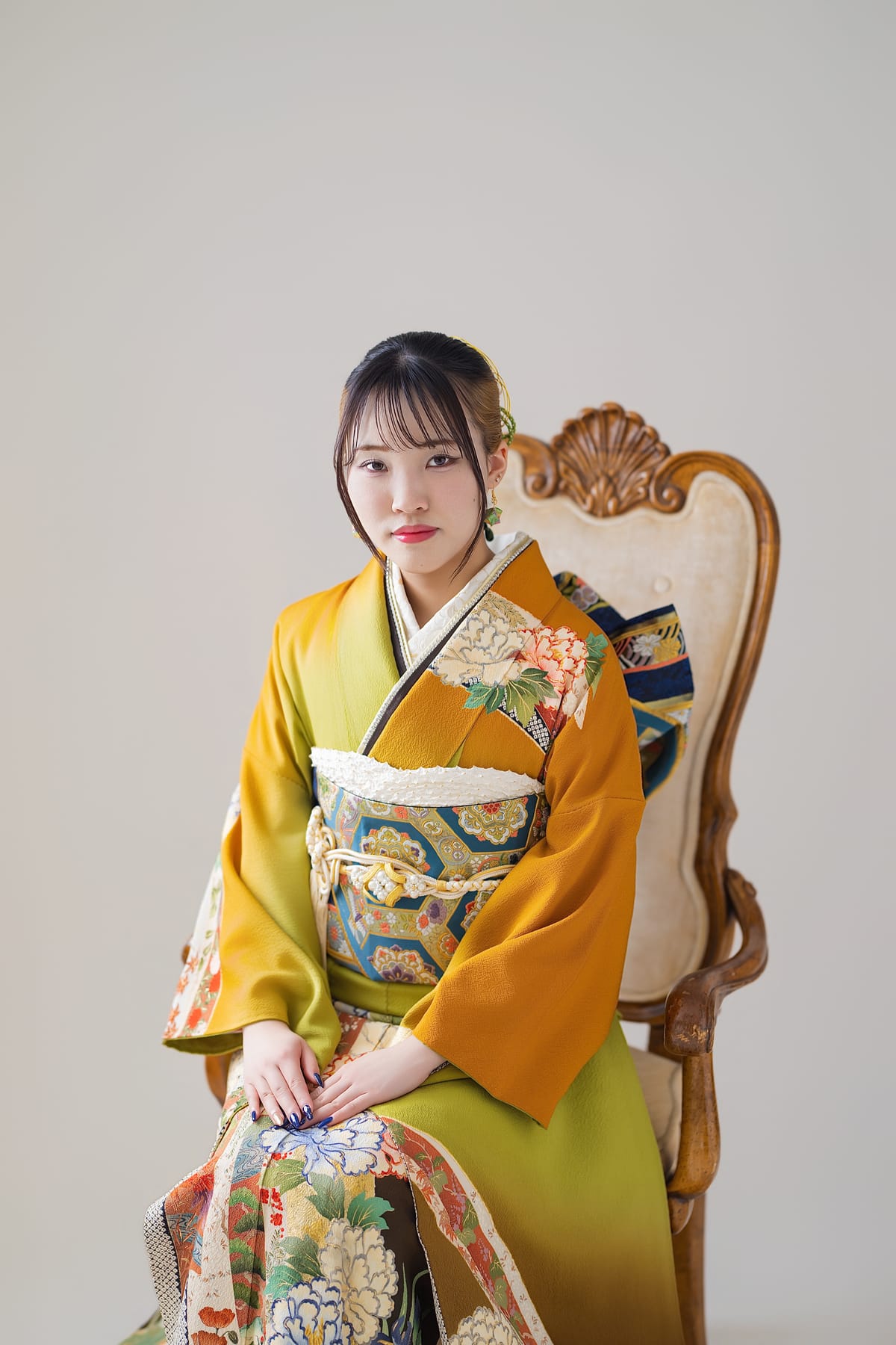 山吹の振袖。椅子に腰かけて手を膝に置いた姿