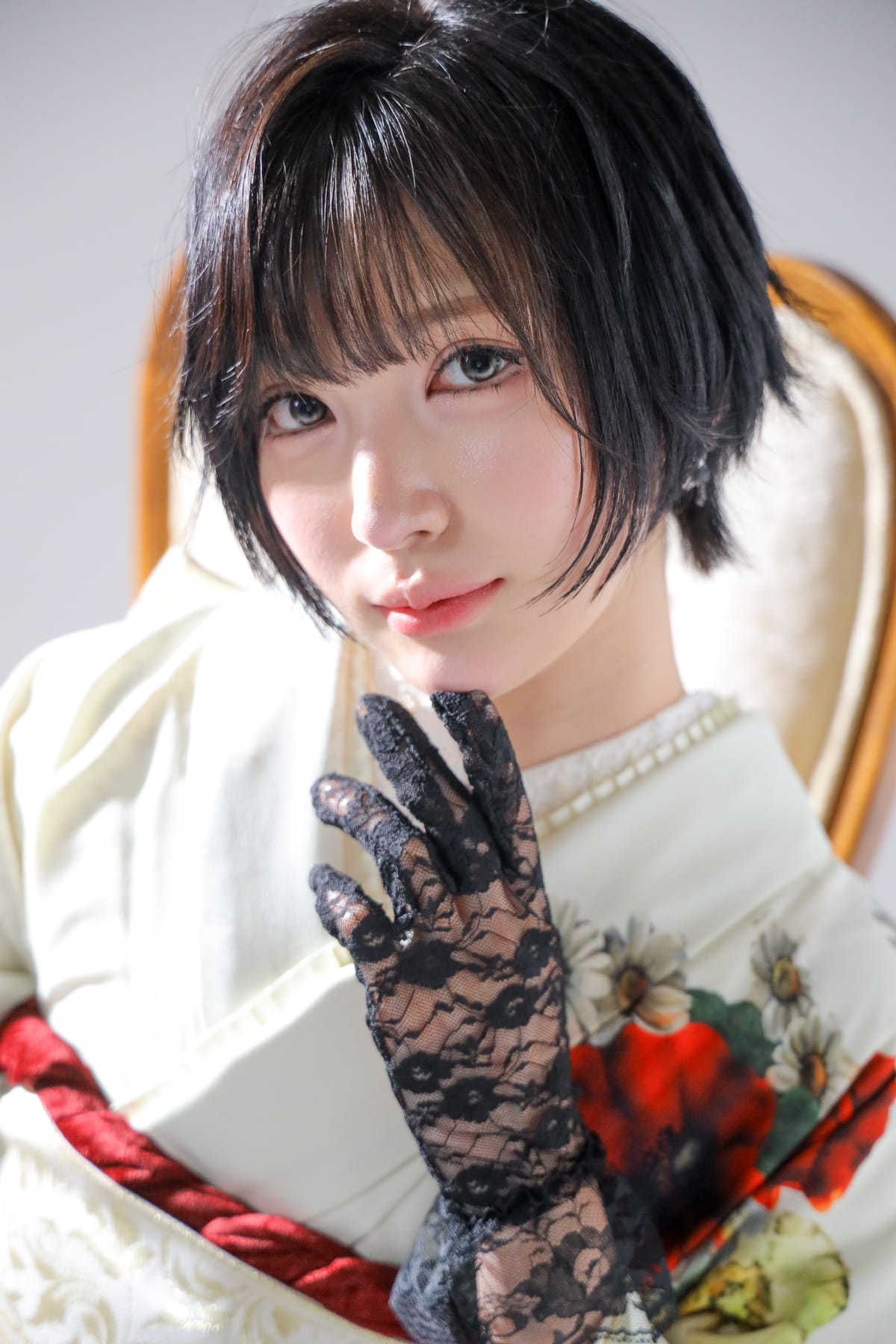 白地に花の振袖。レースの手袋をつけた手を顔の横に添えた寄り
