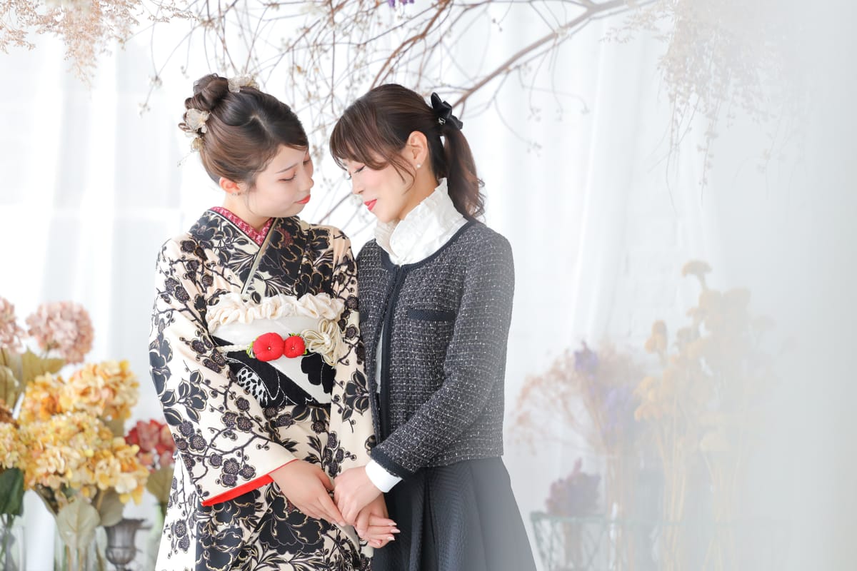 振袖の女性と私服の女性が向き合って手を取る二人の写真