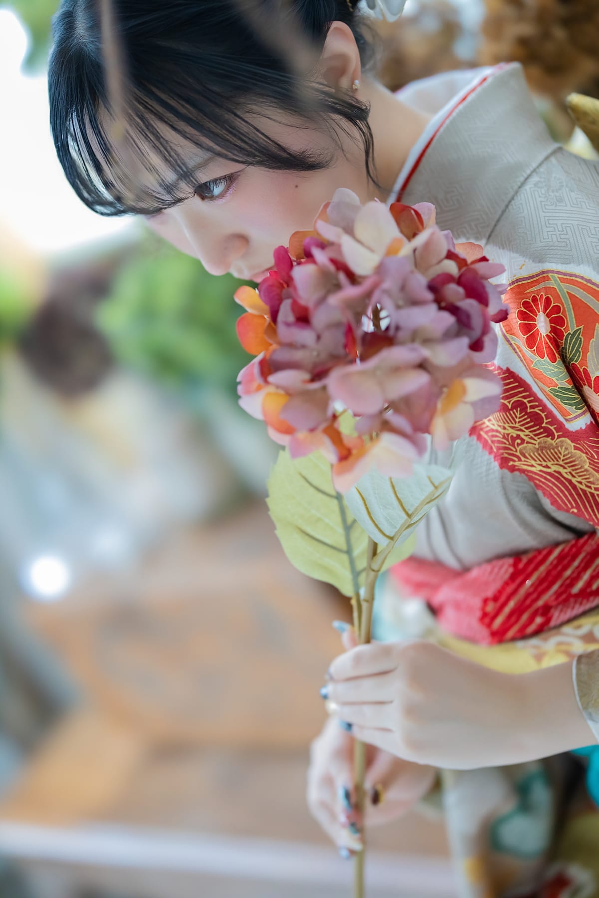 前ボケ越しに、花に顔を寄せた横顔の寄り