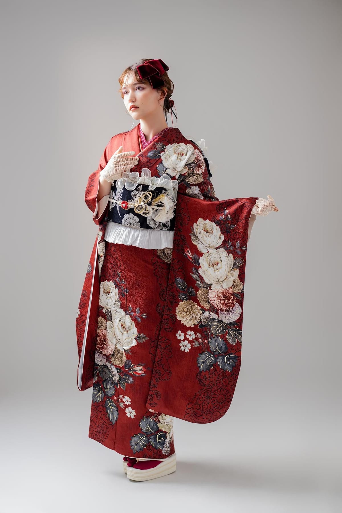 赤地に白と淡紅の牡丹を描いた古典柄の振袖で、袖を大きく広げて撮影した成人式の前撮り写真